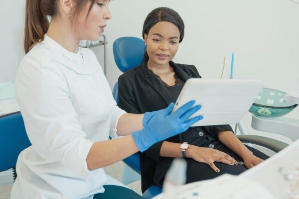 Dentist consulting patient using a tablet in a modern dental clinic.